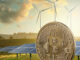 Picture of a Bitcoin with wind vanes and solan panels behind it