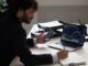 Smart focused Indian broker investor, stock trader using smartphone and laptop to analyze and invert in the financial market of cryptocurrencies, buy or sell crypto coins, planning strategy